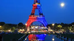 Orang-orang memandang Menara Eiffel yang diterangi cahaya warna-warna khas, dengan pesan bertuliskan "Allez Paris" ("Ayo, Paris"), pada malam menjelang pertandingan final Liga Champions 2025/2026 antara Paris Saint-Germain (PSG) dan Arsenal, Kamis 29 Mei 2026. (Ludovic MARIN/AFP)