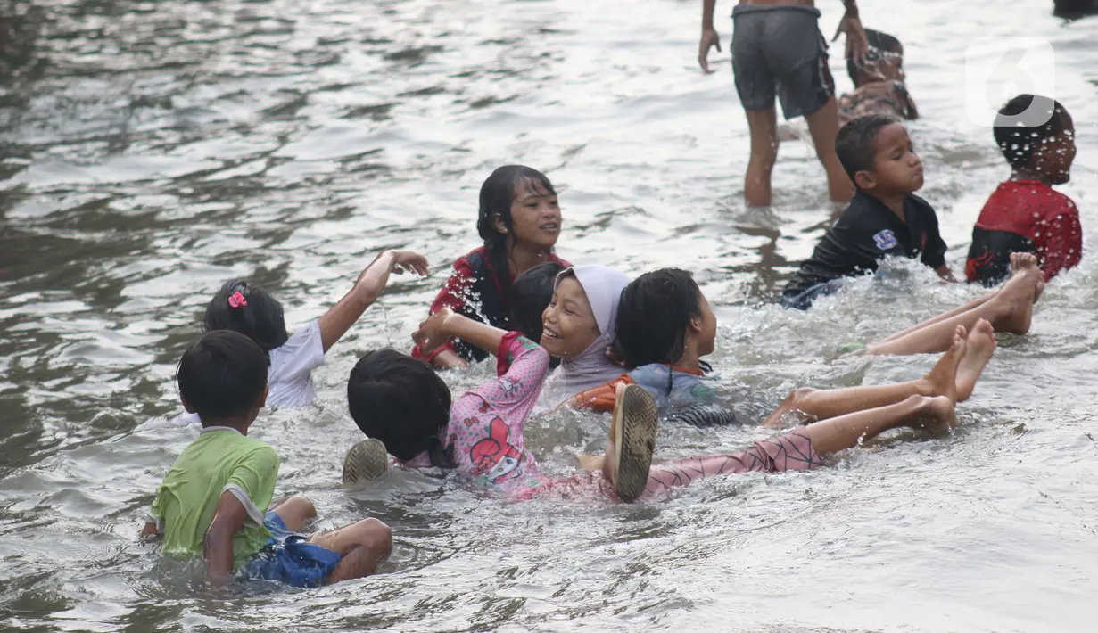 Sejumlah anak-anak bermain di genangan air akibat banjir rob di kawasan pintu masuk Pelabuhan Nizam Zachman, Muara Baru, Jakarta, Jumat (5/6/2020). Banjir rob di Pelabuhan Muara Baru tersebut terjadi akibat cuaca ekstrem serta pasang air laut. (Liputan6.com/Helmi Fithriansyah)