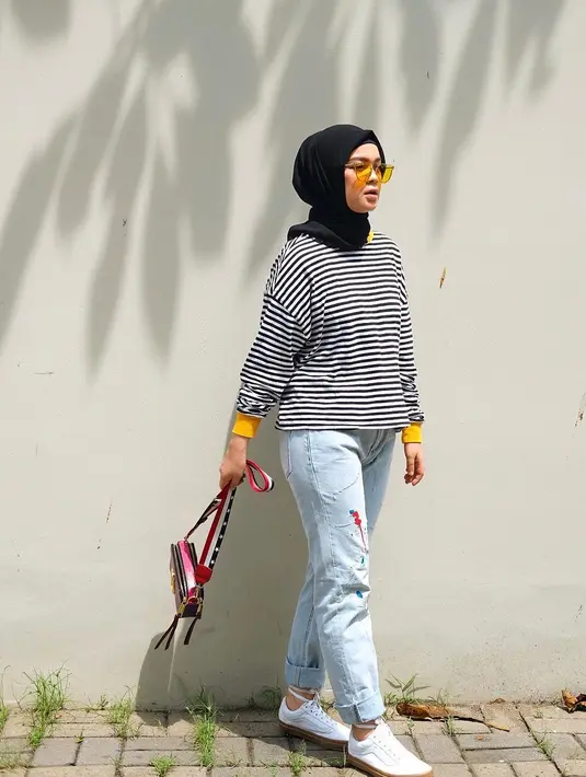 Style kasual seringkali menjadi pilihan Tantri dalam setiap penampilannya. Kali ini, dengan hijab hitamnya Tantri memadukannya dengan ripped jeans dan kaus garis-garis. Ia pun makin kece dengan sneakers putihnya. (Instagram/tantrinamirah)