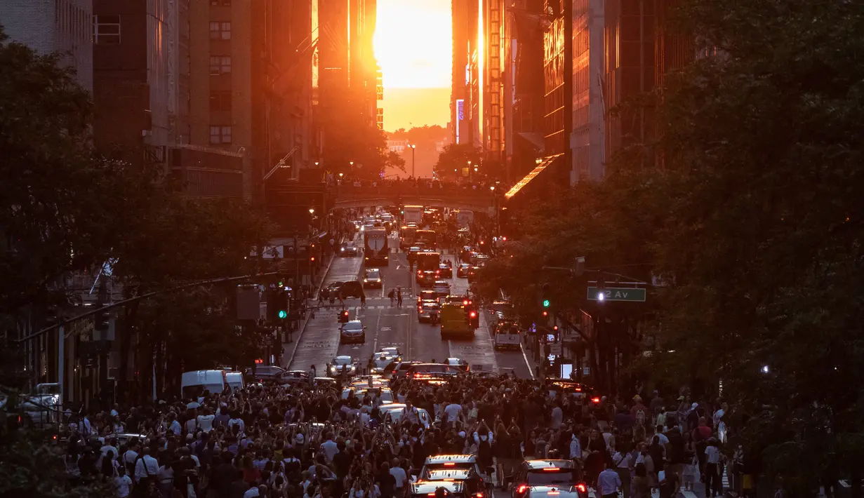 Matahari terbenam di Manhattan ketika fenomena "Manhattanhenge" di 42nd street, New York, Senin (11/7/2022). Manhattanhenge adalah keadaan dimana matahari terbenam tepat berada dalam garis lurus dengan jalanan Manhattan yang melintang dari timur ke barat. (Yuki IWAMURA / AFP)