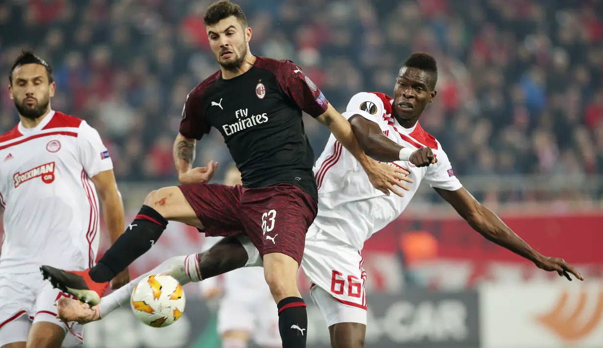Pemain AC Milan Patrick Cutrone dan pemain Olympiakos Piraeus, Pape Abou Cisse berebut bola dalam laga keenam Grup F Liga Europa di Stadion Georgios Karaiskakis, Kamis (13/12). Milan tersingkir dari Liga Europa setelah kalah 1-3. (AP/Petros Giannakouris)