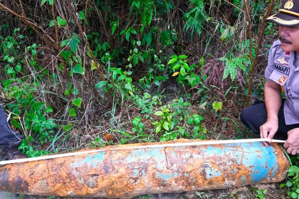 Kapolsek Tenayan Raya Pekanbaru Kompol Hanafi mengukur benda yang diduga bom di lokasi penggalian pipa.
