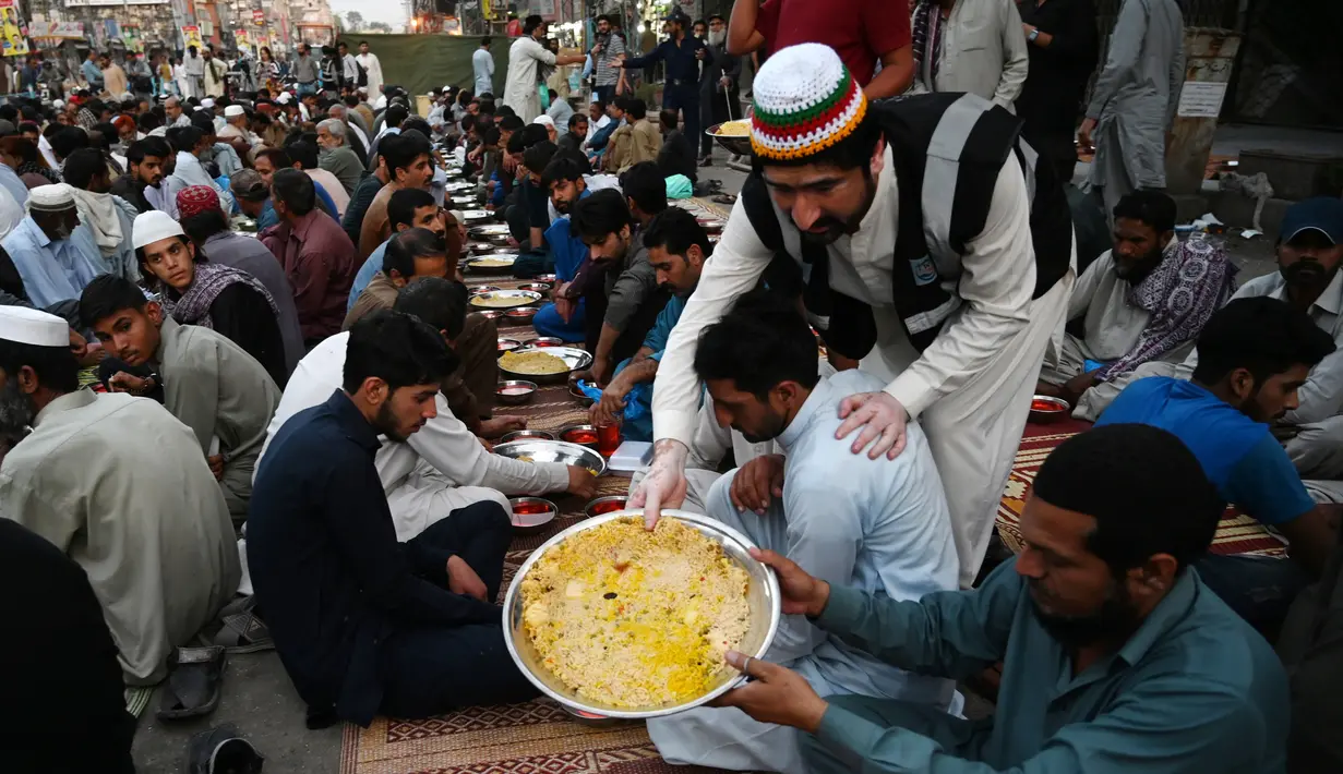 Relawan menyajikan makanan berbuka puasa kepada muslim Pakistan di sepanjang jalan di Rawalpindi pada 7 Mei 2019. Ketika bulan Ramadan mulai di Pakistan, banyak masyarakat muslim memanfaatkan buka puasa gratis yang disponsori oleh badan-badan amal dan orang-orang kaya. (RIZWAN TABASSUM / AFP)