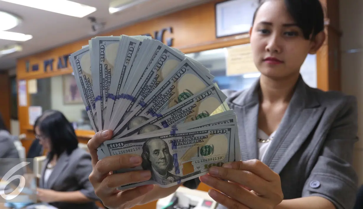 Petugas menunjukkan mata uang Dolar Amerika di toko penukaran uang di Jakarta, Selasa (7/6). Dolar AS kembali melemah terhadap rupiah. Mata uang Paman Sam ini bergerak dikisaran Rp 13.300. (Liputan6.com/Angga Yuniar)