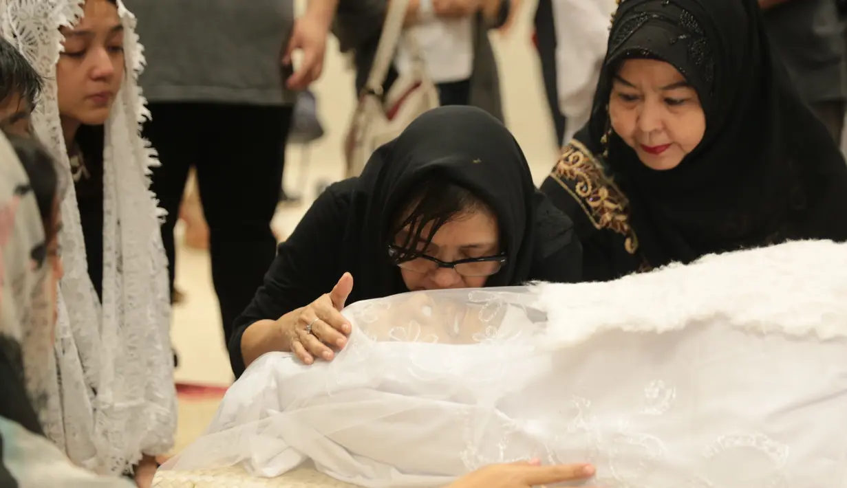 Istri anak bergantian mencium jenazah Yockie yang telah terbujur kaku dan siap dibungkus kain kafan. (Adrian Putra/Bintang.com)