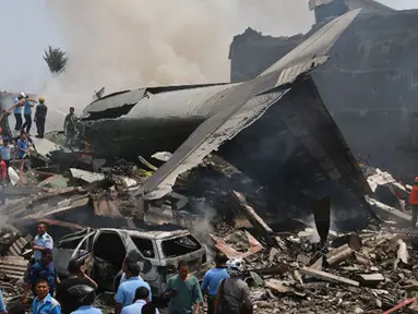 Sejumlah Petugas berusaha melakukan evakuasi pesawat Hercules C-130 yang jatuh di kawasan perumahan di Medan, Selasa (30/6/2015). Hercules C-130 milik TNI AU jatuh tidak lama setelah lepas landas. (AFP PHOTO/Kharisma Tarigan)