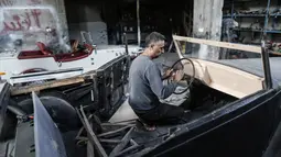 Munir Shindy memasang stir mobil tua di bengkelnya di Kota Gaza (28/10/2019).  Shindi berharap dapat berkendara sambil memamerkan mobilnya namun dia tahu hal itu tidak mungkin dilakukan akibat blokade Israel di Gaza. (AFP Photo/Mahmud Hams)