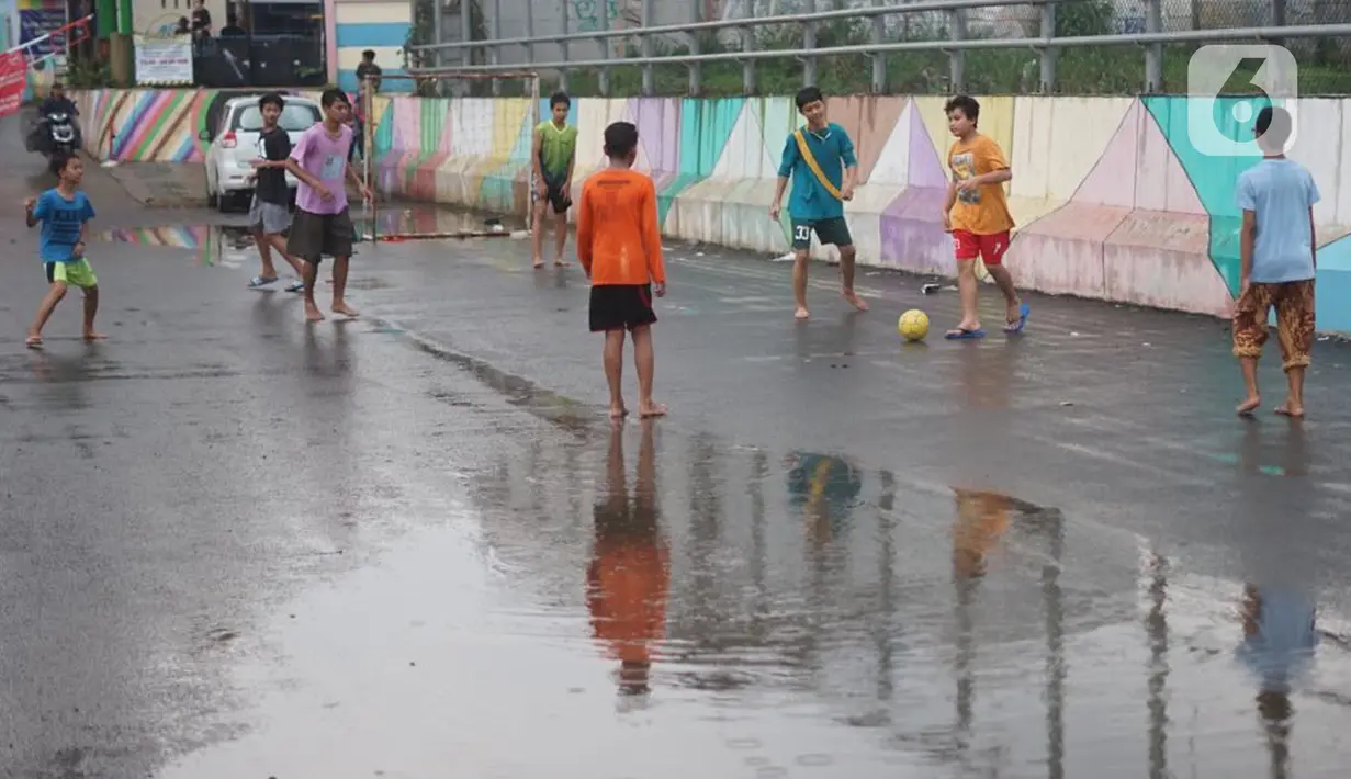 Anak-anak bermain sepak bola di sekitar kawasan Depok, Jawa Barat, Kamis (16/4/2020). Kurangnya sanksi tegas membuat sebagian warga Depok bebas berkeliaran untuk bersosialisasi, meskipun saat ini sedang diberlakukan PSBB untuk mencegah penyebaran Covid-19. (Liputan6.com/Immanuel Antonius)