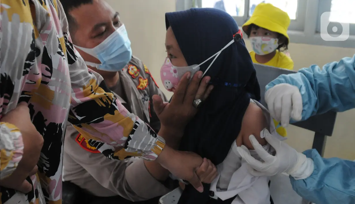 Anggota Polsek Cinere mendampingi murid kelas II saat vaksinasi covid-19 di SDI Al Hidayah, Depok, Selasa (25/1/2022). Mengantisipasi meningkatnya kasus Omicron, pemerintah mempercepat vaksin untuk lansia dan anak-anak, baik itu vaksin dosis pertama, kedua, maupun booster. (merdeka.com/Arie Basuki)