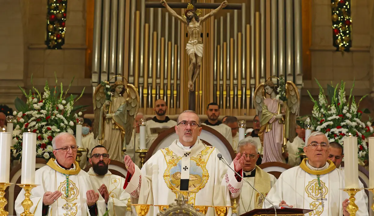 Patriark Latin Yerusalem, Pierbattista Pizzaballa (tengah) memimpin Misa Malam Natal di Kompleks Gereja Kelahiran Yesus, Bethlehem, Tepi Barat, Minggu (25/12/2022). Setelah dua tahun tutup karena COVID-19, jemaat kembali menghadiri ibadah tersebut kendati jumlahnya tidak sebanyak sebelum pandemi. (Ahmad Gharabli/Pool Photo via AP)