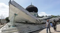 Warga melintas di depan masjid yang roboh usai gempa di Meuredu, Pidie Jaya, Aceh, Rabu (7/11). Selain meruntuhkan bangunan, gempa bumi berkuatan 6,4 SR ini telah menelan banyak korban jiwa. (Antara Foto / Irwansyah Putra / via REUTERS)