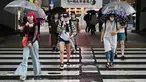 Orang-orang menyeberang di bawah rel kereta api selama hujan yang terisolasi di distrik Akihabara Tokyo (13/8/2022). Hujan lebat yang dibawa oleh Badai Tropis Meari melanda daerah tersebut. (AFP/ Richard A. Brooks)