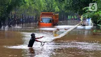 Warga menjala ikan di tengah jalan yang tertutup banjir di kawasan TB Simatupang, Jakarta Selatan, Sabtu (20/2/2021). Banjir terjadi akibat luapan Kali Serua yang berada di pinggir jalan tol. (merdeka.com/Arie Basuki)