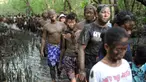 Warga Bali berjalan bersama dengan badan penuh lumpur saat mengikuti mandi lumpur tradisional atau yang dikenal sebagai Mebuug-buugan di desa Kedonganan, Bali (18/3). (AFP/Sony Tumbelaka)