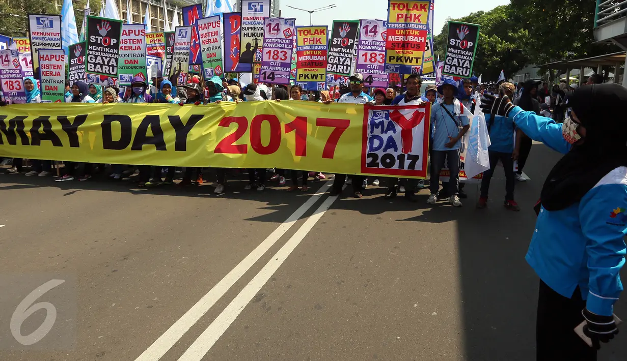 Massa buruh dan pekerja dari berbagai daerah membentangkan spanduk dalam peringatan May Day atau Hari Buruh Internasional di Jalan MH Thamrin, Jakarta, Senin (1/5). Massa buruh berjalan sambil membawa poster-poster tuntutan. (Liputan6.com/Johan Tallo)