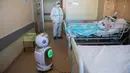 Sebuah robot ditempatkan di depan pasien yang sedang dirawat di unit perawatan intensif rumah sakit 'Ospedale di Circolo', di Varese, Italia, 8 April 2020. Sebanyak enam unit robot yang berjalan di atas roda ini membantu kinerja staf medis dalam merawat pasien virus corona Covid-19. (AP/Luca Bruno)