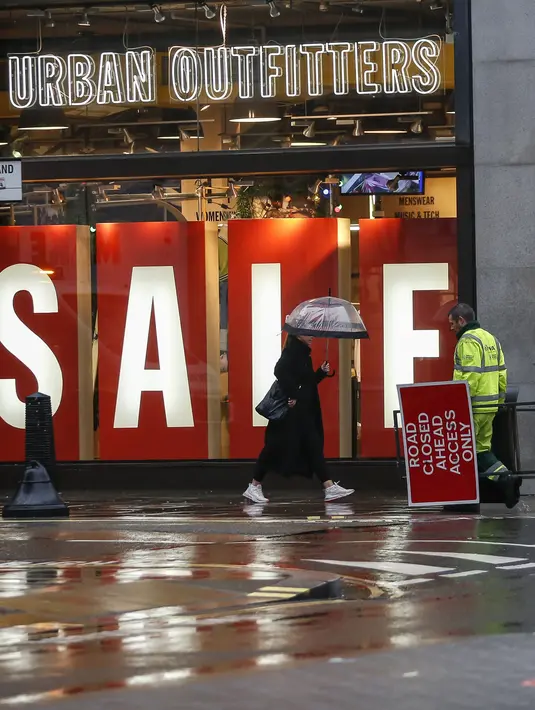Seorang pria yang membawa rambu penutupan jalan terlihat di depan toko yang tutup, London, Inggris, 21 Desember 2020. Warga Inggris didesak berperilaku seolah-olah mereka sudah terjangkit COVID-19, terutama di area-area yang berada di bawah pembatasan Tingkat Empat yang baru. (Xinhua/Han Yan)