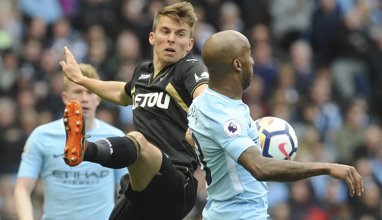 Pemain Swansea, Tom Carroll (kiri) mencoba menghalau bola dari pemain Manchester City, Fabian Delph pada lanjutan Premier League di Etihad Stadium, Manchester, (22/4/2018). Manchester City menang 5-1. (AP/Rui Vieira)