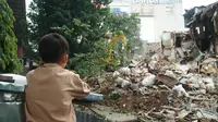 Seorang bocah menyaksikan alat berat yang digunakan Satpol PP Kota Bandung untuk meratakan tanah di lahan proyek rumah deret. (Liputan6.com/Huyogo Simbolon)