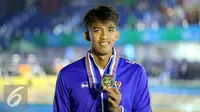 Perenang Jawa Barat, Triadi Fauzi S memamerkan medali kelas 100m gaya bebas putra di Gelanggang Renang FPOK UPI, Bandung, Senin (19/9). Triadi berhasil meraih emas sekaligus memecahkan rekor PON dengan 50,49 dtk. (Liputan6.com/Helmi Fithriansyah)