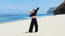 Begitu pun ketika ia di pantai, Tania asik berpose dengan mengenakan crop top hitam longsleeve dipadukan dengan pants length. Sunglass pun digunakan untuk menghalau sinar matahari. Dok. Instagram @taniawidjaya