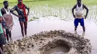 Penduduk lokal berkumpul di sekitar kawah yang diciptakan oleh batu yang diduga meteorit, sebesar sepak bola, yang ditemukan di sawah di Desa Mahadeva di negara bagian Bihar di India. (AFP)