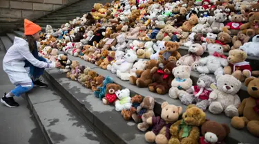 Seorang siswa meletakkan satu boneka beruang atau Teddy Bears di tangga Concert Hall, Berlin, Kamis (15/3). Kelompok bantuan kemanusiaan World Vision melakukan aksi pengumpulan 740 boneka beruang. (AFP PHOTO/Odd ANDERSEN)