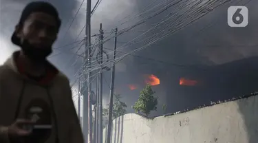 Asap hitam membumbung dari atas Gudang JNE Express yang terbakar di Jalan Pekapuran Raya, Depok, pada Senin (12/9/2022). JNE menjamin barang milik konsumen yang rusak  dalam peristiwa kebakaran gudang di Depok akan diganti. (Liputan6.com/Herman Zakharia)