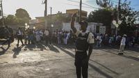Seorang anggota polisi nasional mengontrol keamanan di sebuah jalan di Port-au-Prince, Haiti, Sabtu (21/1/2023). Geng yang kuat dan bersenjata lengkap menguasai sebagian besar negara dan kerap kali menculik orang dan menahan mereka untuk tebusan. (AP Photo/Megan Janetsky)