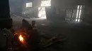 Sejumlah imigran menghangatkan tubuh mereka di sebuah gudang kosong di Belgrade, Serbia (8/1). Mereka harus bertahan hidup dibawah cuaca ekstrem dengan kebutuhan yang seadanya. (AP Photo/Darko Vojinovic)