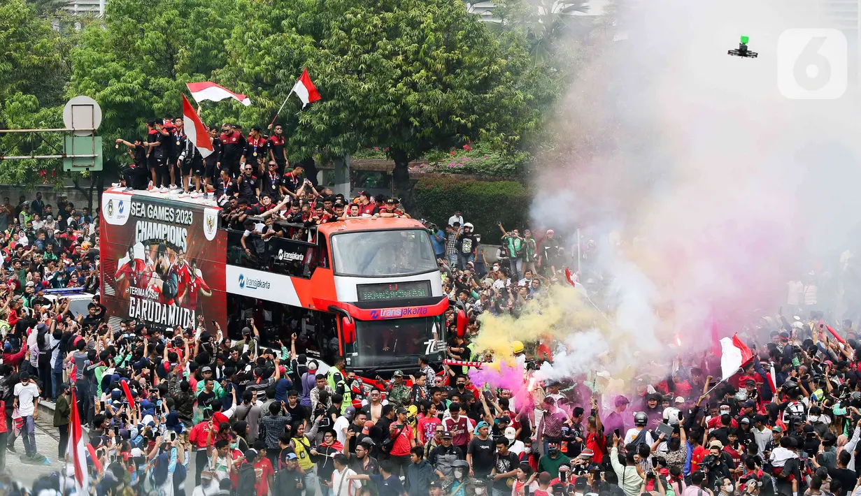 Suara petasan dan flare dinyalakan para pendukung saat kedatangan pemain Timnas U-22 Indonesia yang menaiki bus tingkat Transjakarta. (Liputan6.com/Herman Zakharia)
