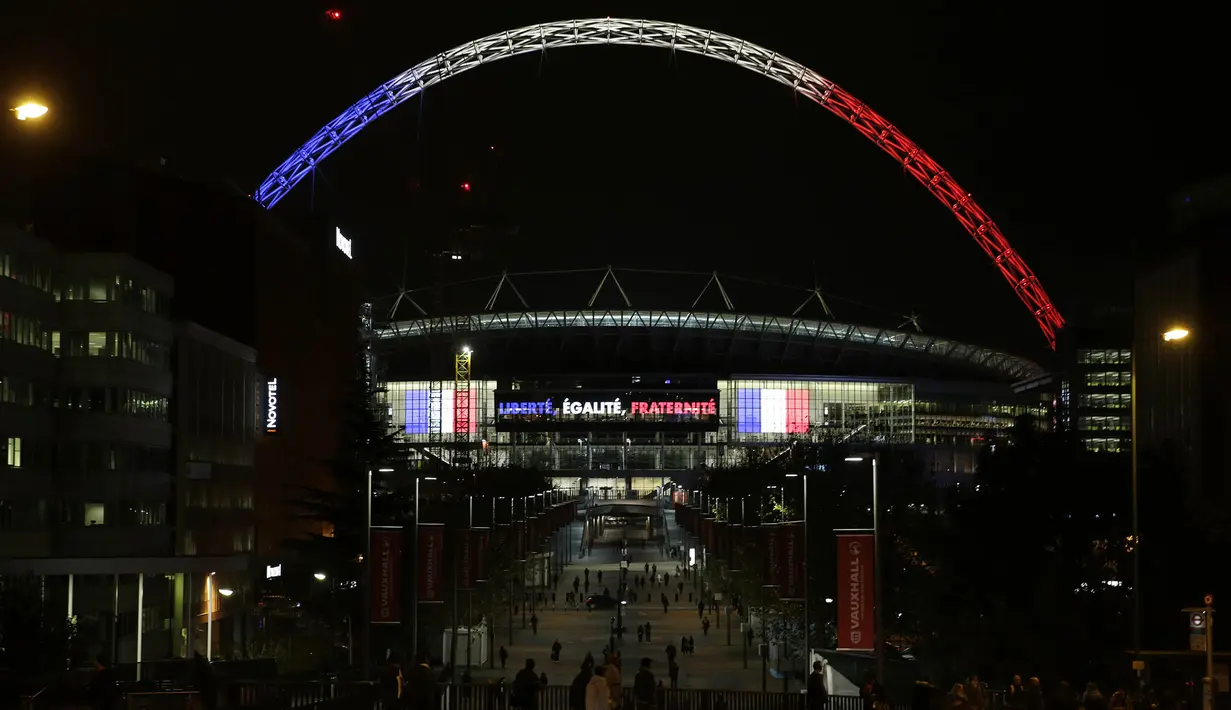 Sejumlah warga beraktifitas di sekitar Stadion Wembley yang dihiasi lampu berwarna bendera Prancis, Senin (16/11/2015). Lampu ini merupakan bentuk belasungkawa Inggris terhadap serangan terror di Paris. (Action Images via Reuters/Henry Browne)