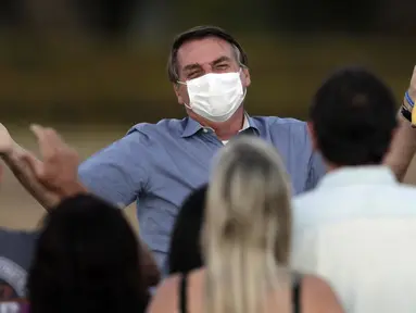 Presiden Brasil Jair Bolsonaro mengenakan masker saat berbicara dengan para pendukungnya di luar Istana Alvorada, Brasilia, Brasil, Jumat (24/7/2020). Jair Bolsonaro dinyatakan positif terinfeksi COVID-19 pada 7 Juli lalu. (AP Photo/Eraldo Peres)