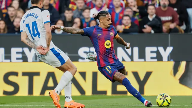 Raphinha dari Barcelona, kanan, menendang bola dengan diadang oleh Nahuel Tenaglia dari Alaves