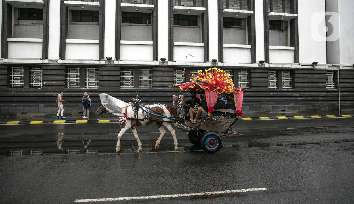 Andong melintas di Kota Tua saat uji coba penerapan zona rendah emisi, Jakarta, Minggu (20/12/2020). Selama penerapan zona rendah emisi, kawasan Kota Tua hanya bisa dilalui pejalan kaki, pesepeda, angkutan umum, dan kendaraan khusus yang lulus uji emisi. (Liputan6.com/Faizal Fanani)