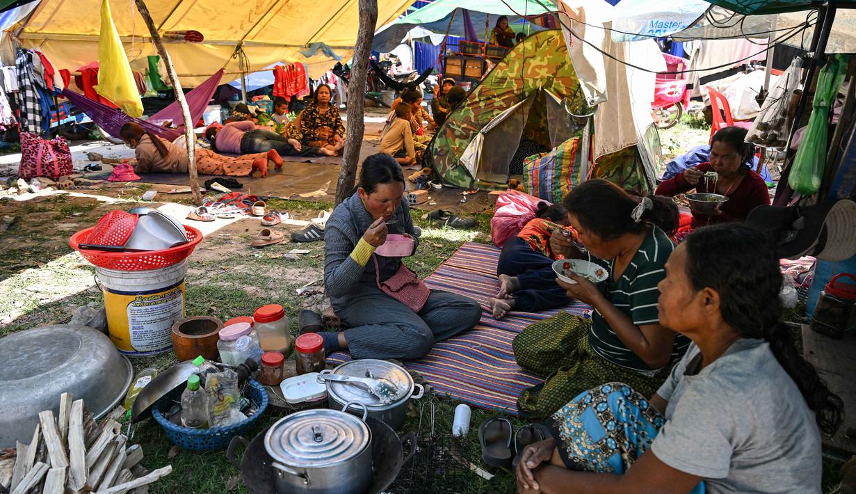 Serangan terjadi setelah insiden tembak-menembak yang dilaporkan melukai dua prajurit Thailand sehari sebelumnya. Tampak dalam foto, warga makan siang di luar sebuah kuil setelah dievakuasi menyusul bentrokan di sepanjang perbatasan Kamboja-Thailand, di provinsi Siem Reap pada Selasa 9 Desember 2025. (TANG CHHIN SOTHY/AFP)