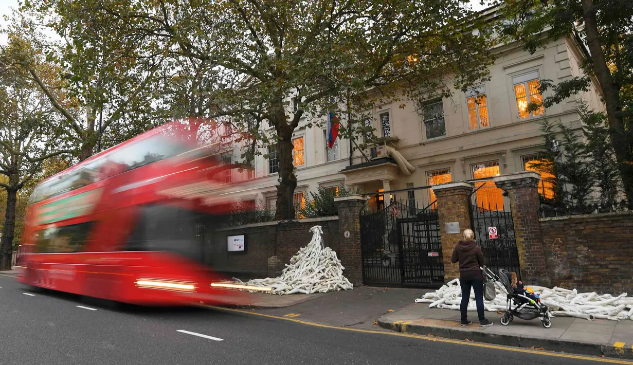 Pejalan kaki mengambil gambar tumpukan lengan manekin di depan pintu masuk Kedutaan Besar (Kedubes) Rusia di London, Kamis (3/11). Pengunjuk rasa menumpuk sekitar 800 bagian lengan manekin sebagai bentuk protes terhadap Moskow. (REUTERS/Toby Melville)