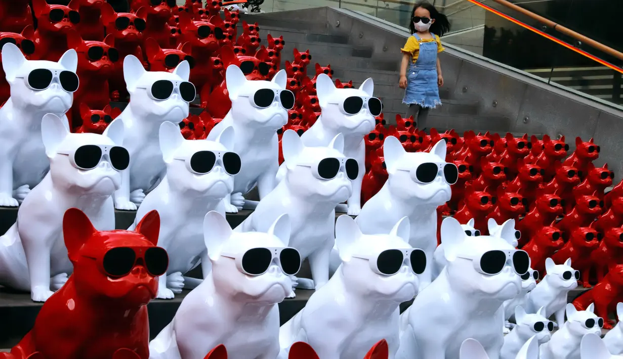 Seorang anak berdiri di dekat speaker audio yang berbentuk anjing mengenakan kacamata di distrik perbelanjaan di Beijing, China (3/5). Speaker anjing yang jadi seni instalasi ini cukup menyita perhatian warga dan juga turis. (AP Photo / Ng Han Guan)