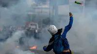 Aktivis oposisi Venezuela bentrok dengan polisi anti huru hara saat demonstrasi menentang Presiden Nicolas Maduro di Caracas,  Venezuela, Rabu (26/4). Hingga kini, bentrokan antara demonstran dan polisi telah menyebabkan 26 orang tewas. (AFP PHOTO) 