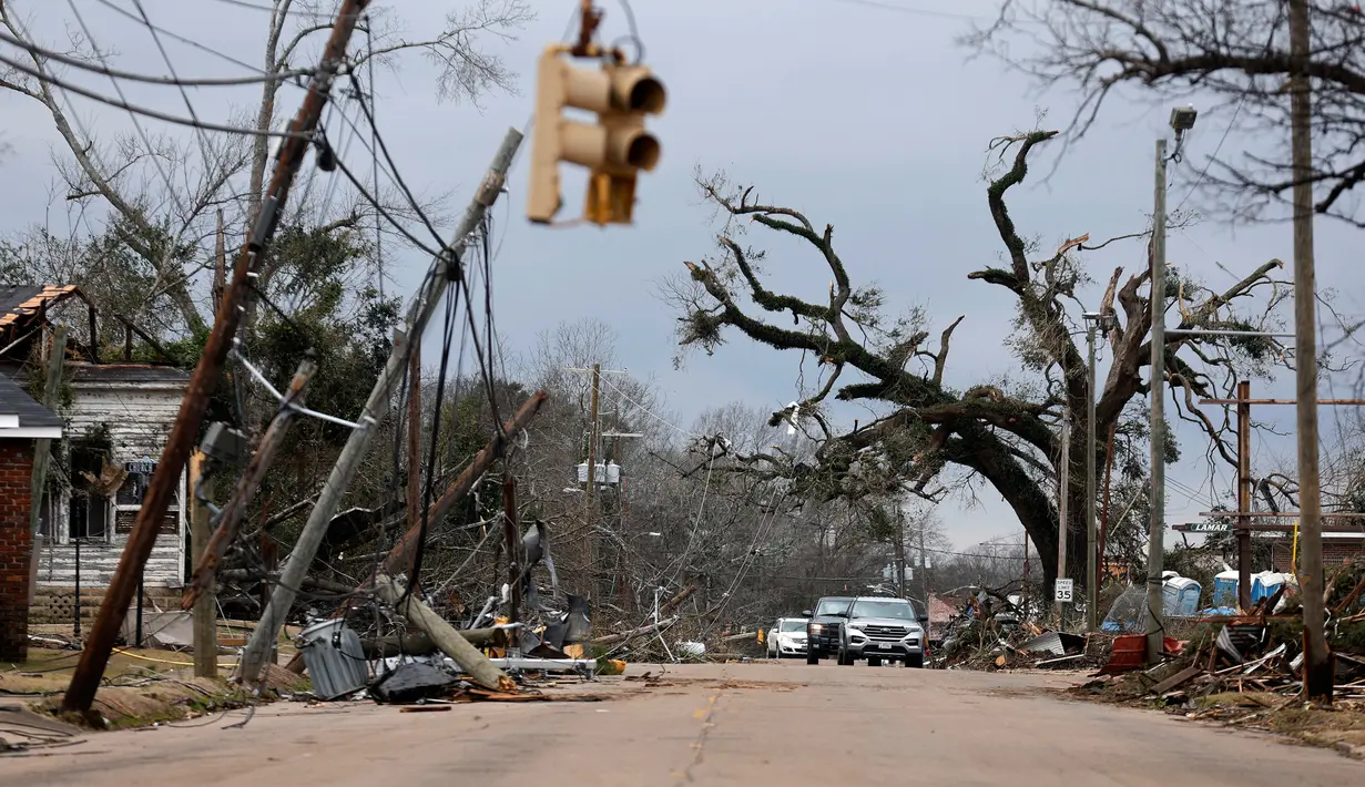 Mobil melewati pepohonan dan kabel listrik yang tumbang setelah tornado di Chestnut Blvd, Selma, Alabama, Amerika Serikat, 13 Januari 2023. Badai menyebabkan pemadaman listrik yang berdampak terhadap ribuan orang di empat negara bagian. (AP Photo/Stew Milne)