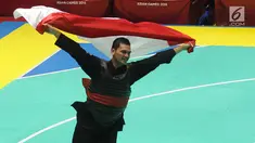 Pesilat Indonesia, Aji Bangkit Pamungkas mengibarkan bendera Merah Putih usai mengalahkan pesilat Singapura Sheik Alauddin dalam babak final Kelas I Putra Asian Games 2018 di TMII, Jakarta, Senin (27/8). (Merdeka.com/Arie Basuki)