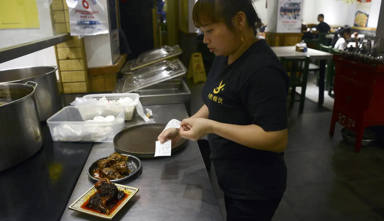 Seorang pelayan menyiapkan menu kepala kelinci di sebuah restoran di Chengdu, ibu kota Provinsi Sichuan di barat daya China, 8 September 2016. Otak kelinci di negeri tirai bambu ini menjadi salah satu menu favorit warga lokal maupun asing. (WANG ZHAO/AFP)
