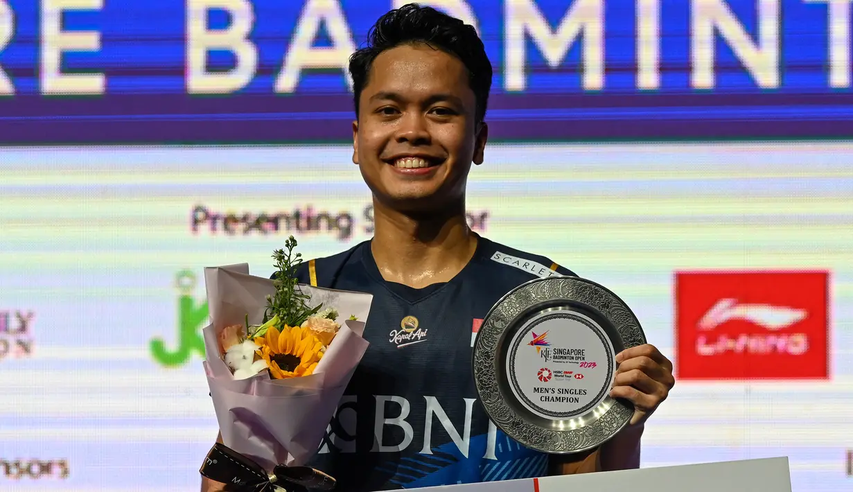 Pebulu tangkis tunggal putra Indonesia, Anthony Sinisuka Ginting berpose dengan trofi juara Singapore Open 2023 setelah mengalahkan wakil Denmark, Anders Antonsen di laga final dengan dua game langsung 21-16, 21-13 di Singapore Indoor Stadium, Singapura, Minggu (11/6/2023). (AFP/Roslan Rahman)
