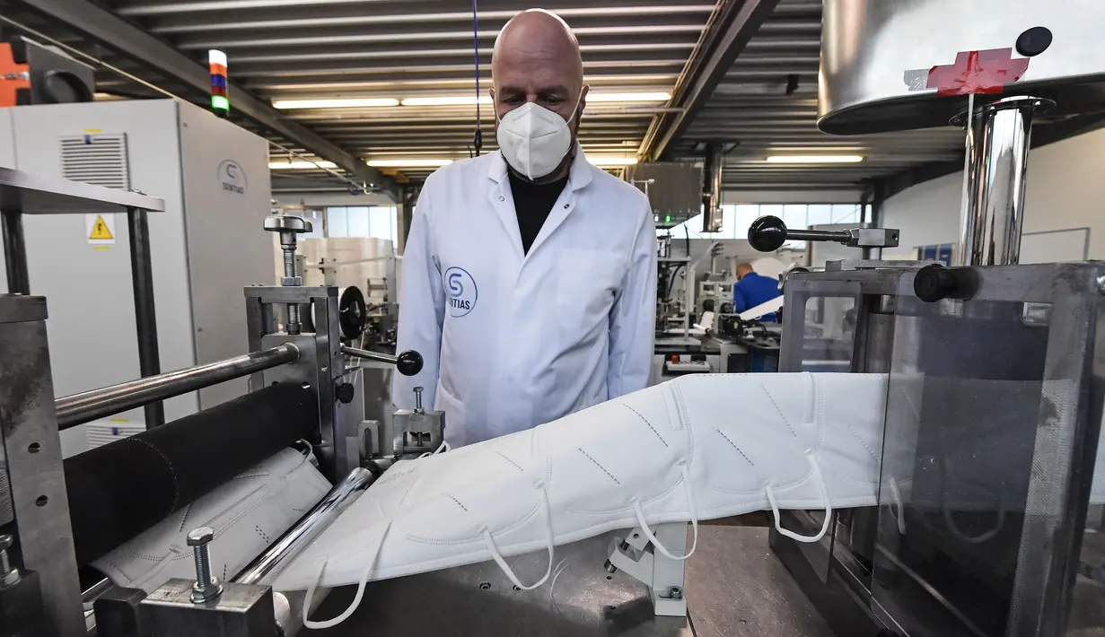 Manajer Christian Vorbau dari produsen masker Sentias mengawasi produksi masker FFP2 di Wuppertal, Jerman, Kamis (28/1/2021). Jerman mewajibkan masker medis jenis KN95 atau FFP2 digunakan saat bepergian dengan transportasi umum atau perbelanjaan. (AP Photo/Martin Meissner)