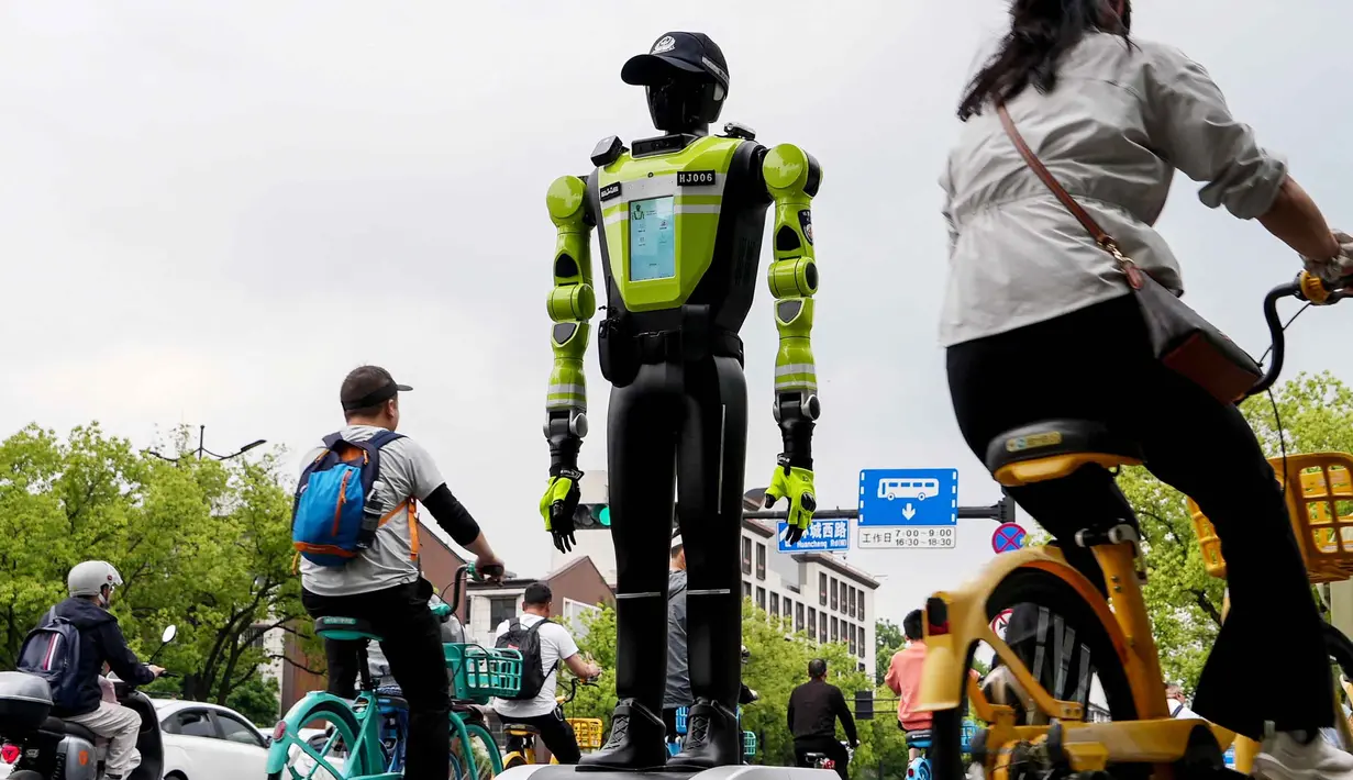 Inovasi ini diharapkan dapat meningkatkan efisiensi, keselamatan, serta kualitas tata kelola perkotaan di tengah meningkatnya mobilitas masyarakat. Tampak dalam foto, orang-orang bersepeda melewati robot polisi humanoid di Hangzhou, provinsi Zhejiang Timur, Tiongkok pada Minggu 3 Mei 2026. (Agatha CANTRILL/AFP)