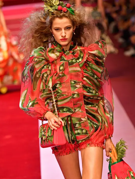 Seorang model berpose di atas catwalk dengan membawa tas besar mirip tas pasar dan mengisinya dengan sayuran untuk koleksi Dolce & Gabbana Spring/Summer 2018 di Milan Fashion Week, Minggu (24/9). (AFP PHOTO / Andreas SOLARO)