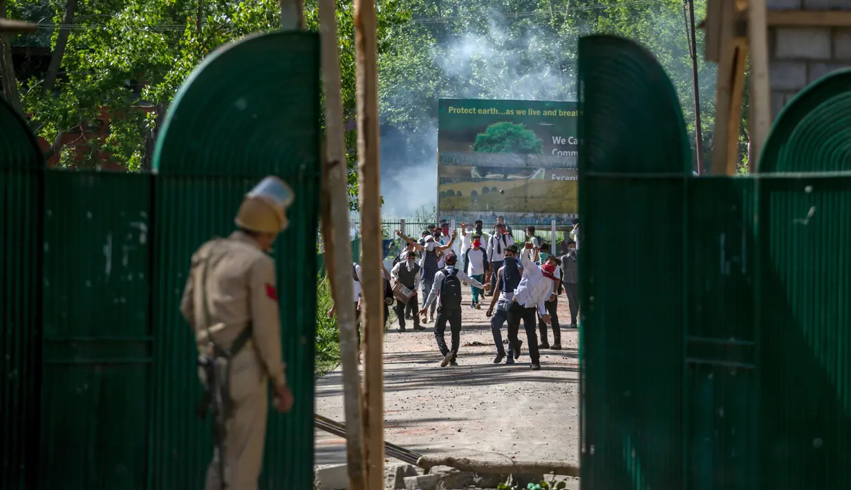 Sejumlah mahasiswa Kashmir melempar batu ke polisi India yang berdiri di gerbang sebuah perguruan tinggi di Srinagar, Kashmir yang dikuasai India, (23/5). (AP Photo/Dar Yasin)