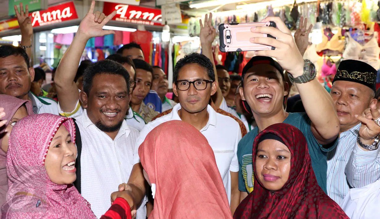 Cawagub DKI Jakarta, Sandiaga S Uno (tengah) disambut pendukungnya saat sosialisasi di pasar Blok A Tanah Abang, Jakarta, Senin (26/12). Dihadapan para pedagang, Sandi mensosialisasikan beberapa program andalannya. (Liputan6.com/Helmi Fithriansyah)
