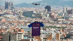 Sebuah drone menerbangkan jersey terbaru milik Barcelona untuk musim 2018/2019 saat diperkenalkan kepada publik di Montjuic Swimming Pool, 19 Mei 2018. Motif seragam Blaugrana sendiri masih menggunakan warna andalannya, merah dan biru. (AFP/Josep LAGO)