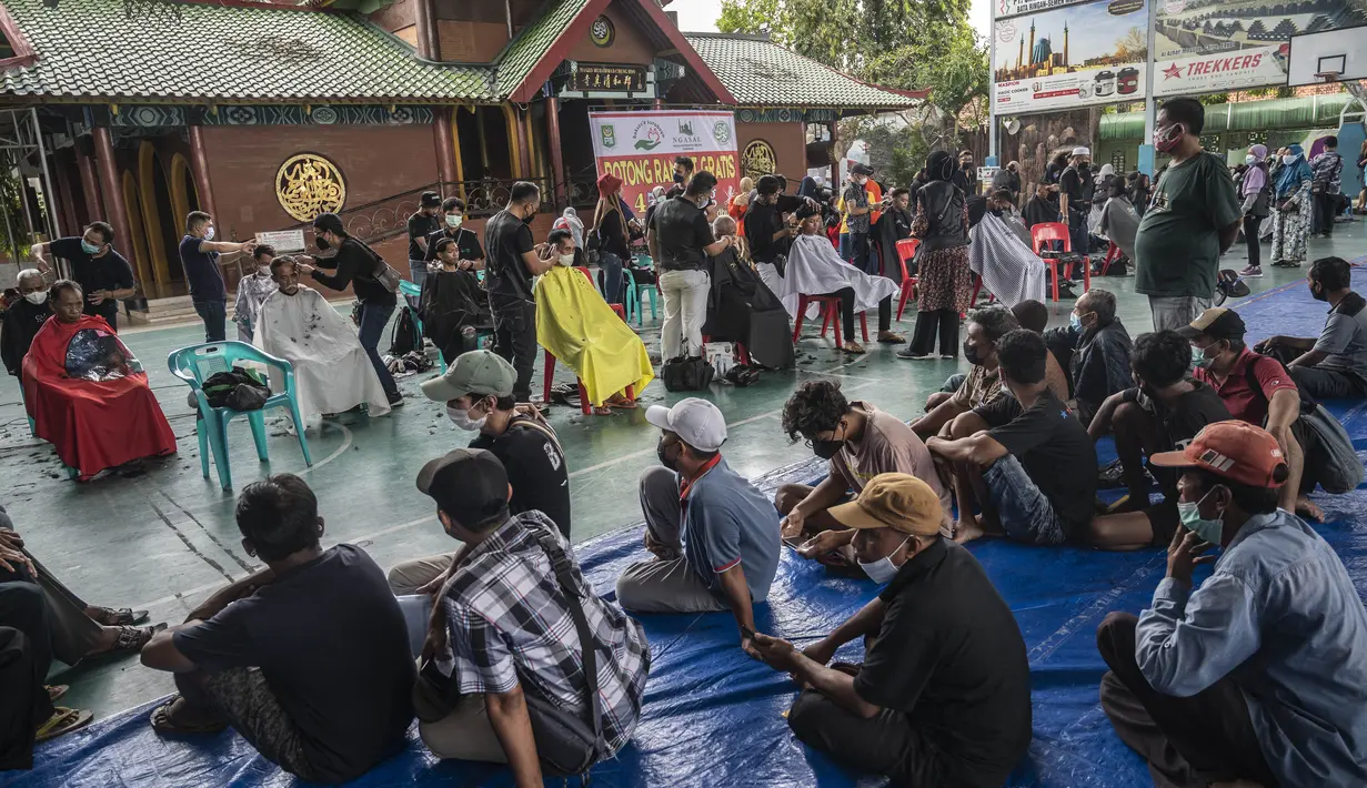 Penata rambut memberikan potongan rambut gratis sebagai bagian dari amal Muslim untuk yang membutuhkan saat umat Islam di seluruh dunia merayakan bulan suci Ramadhan di Muhammad Cheng Hoo di Surabaya (18/4/2022). (AFP/Juni Kriswanto)